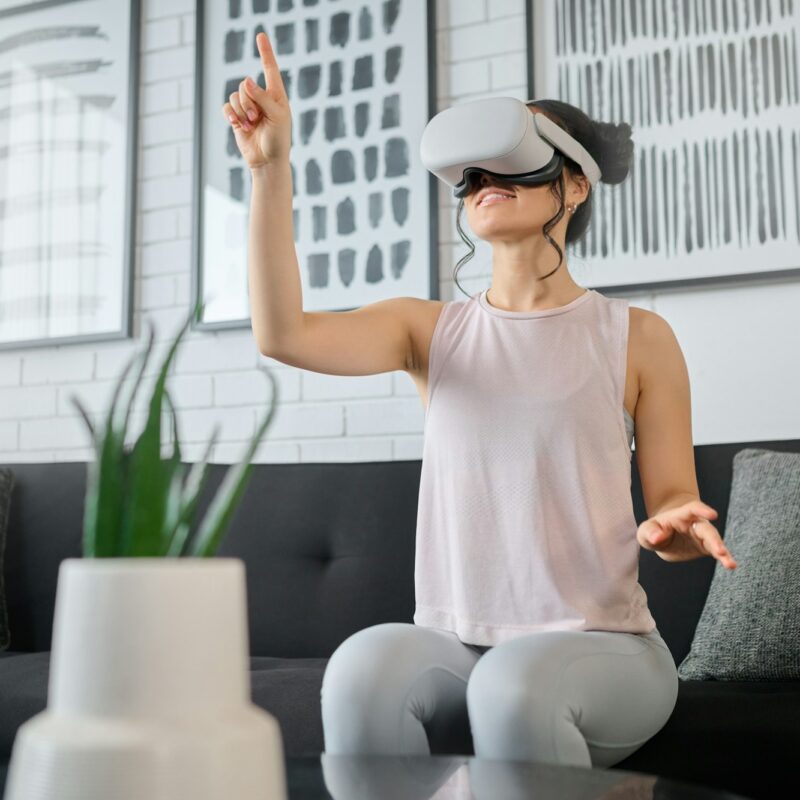 Virtual reality, metaverse and gaming with a woman in the living room of her home using a headset t
